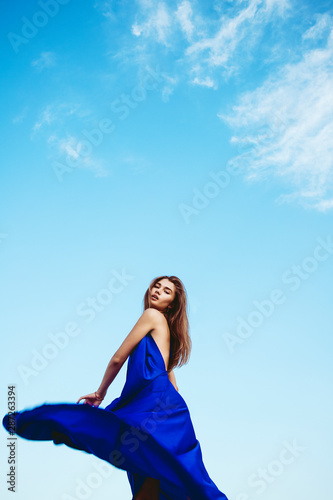Beautiful girl in a blue dress walking on the beach on Bahamas. Outdoor shot. Summer vacation concept.