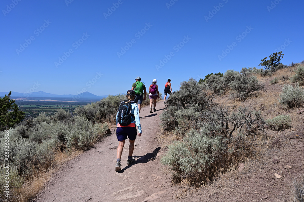 Hikers on Misery Ridge Trail in Smith Rock State Park near Terrebonne, Oregon on a cloudless summer day.