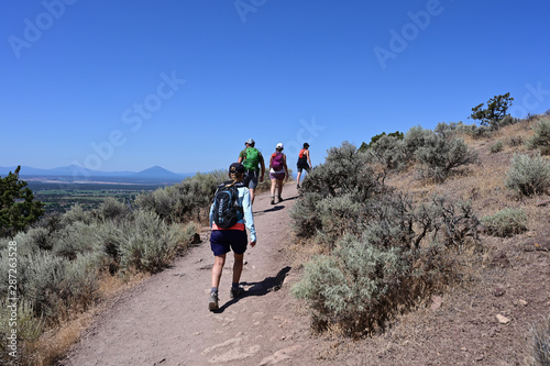 Hikers on Misery Ridge Trail in Smith Rock State Park near Terrebonne, Oregon on a cloudless summer day.