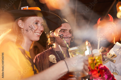 Sticker Group of adult friends wearing Halloween costumes toasting while enjoying party