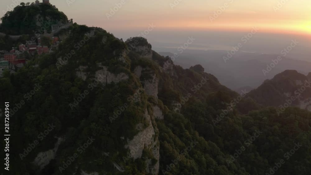 Wundangshan Taoist mountain monastery aerial tilt up orbit across lush summit greenery & misty landscape. Wundangshan Taoist mountain monastery aerial tilt up orbit across lush summit greenery & misty landscape.