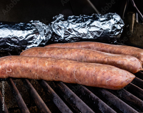 Mild Italian sauasge and baked potatoes on the grill. Calgary, Alberta, Canada photo