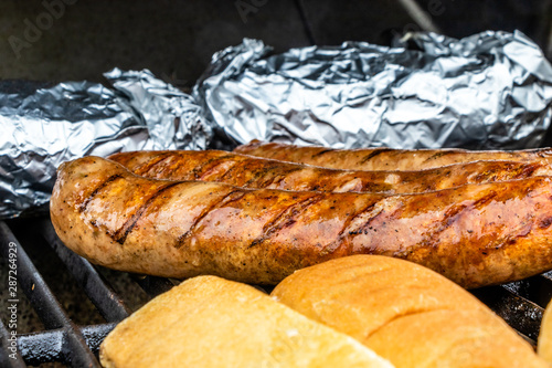 Mild Italian sauasge, buns and baked potatoes on the grill. Calgary, Alberta, Canada photo