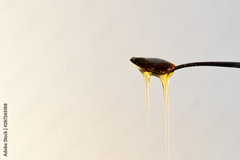 Honey dripping off a spoon with a white background and copyspace. Honey dripping off a spoon with a white background and copyspace.