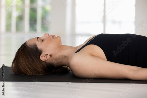Young woman with closed eyes practicing yoga, Savasana, Corpse pose