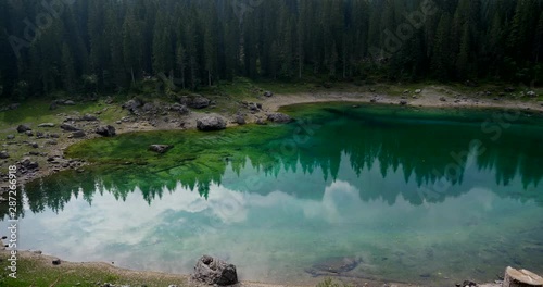 Lake Carezza, mountain lake famous for the dark green color and the beautiful panorama of mountains in the background. Reflection of the Rose Garden in the Lake. South Tirol, Italy photo