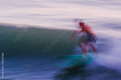 Panned shot of a surfer catching a wave, unrecognizable person