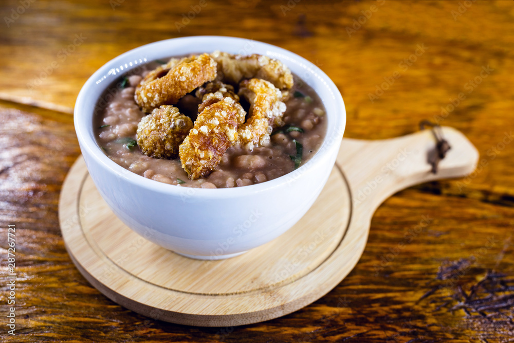 Mashed bean cracklings called Tutu de Feijao in Brazil. Brazilian beans with cabbage, large piece of pork rinds and beans. Rural food.