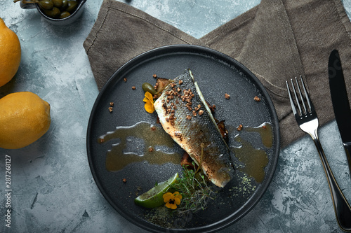 Grilled seabass with eggplant and lime. Horizontal top view, top shot. Copy space, gray concrete marble background, soft light. Food Fashion Photo.