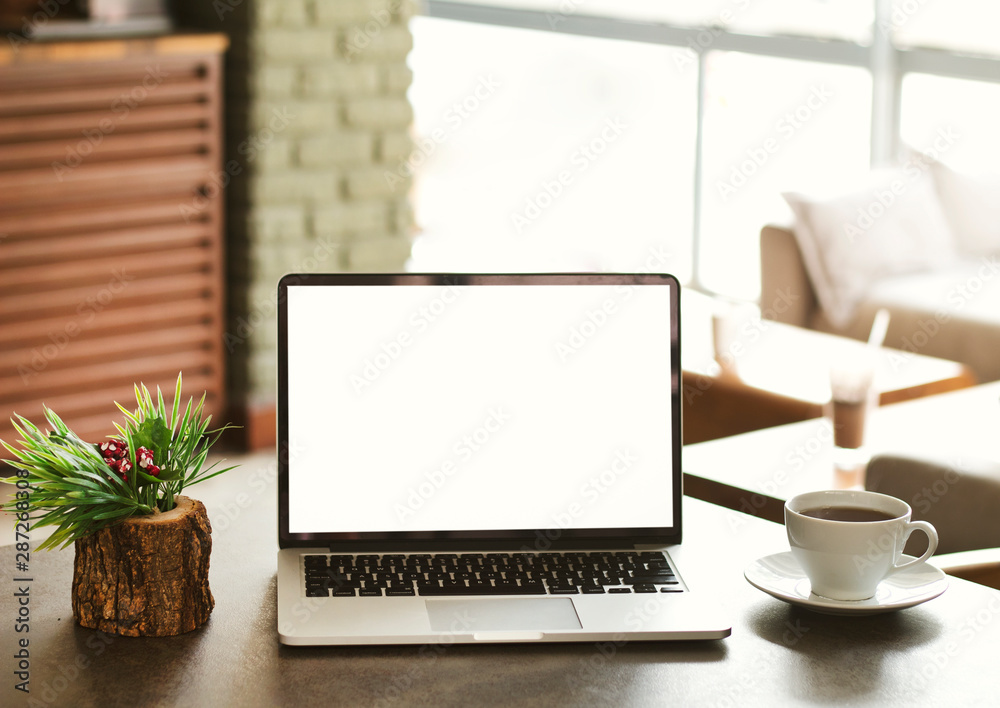 Blank screen laptop computer on table top with blur cafe restaurant with abstract bokeh light defocused background Blank screen laptop computer on table top with blur cafe restaurant with abstract bokeh light defocused background