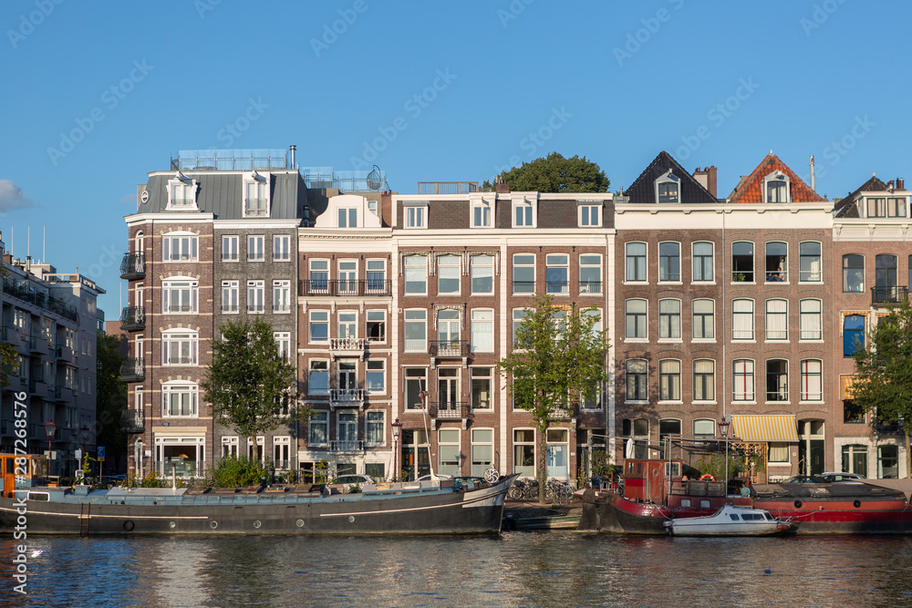 Urban city view of Amsterdam canal with mobile water living boats at sunset