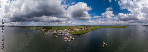 Aerial wide panorama of the small village Durgerdam near Amsterdam with its recreational port area with many sailboats docked against a blue sky with clouds photo