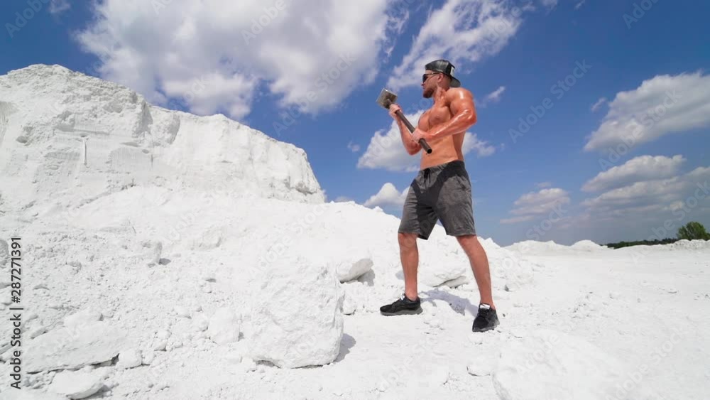 Sportsman with hammer on the mountain. Muscular shirtless guy with ...