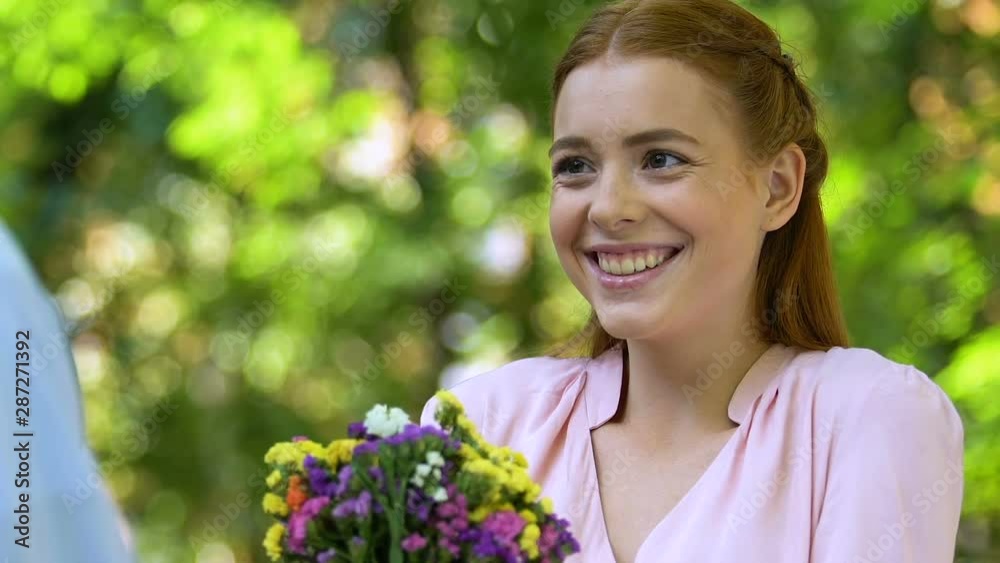 Pretty girl rejoicing flowers from boyfriend, first romantic feelings in teenage Pretty girl rejoicing flowers from boyfriend, first romantic feelings in teenage