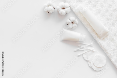 Cotton pads, swabs, cream on white background top view copyspace