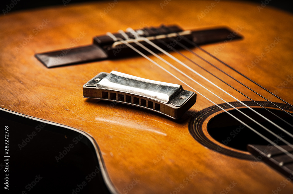 vintage harmonica on acoustic guitar Photos | Adobe Stock