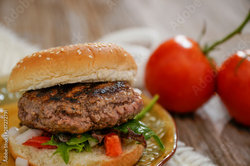 Homemade hamburger on plate with fixins. Delicious sandwich hamburger with meat or pork ham cheese and fresh vegetable. Hamburger or sandwich is the popular fast food for brunch or lunch. photo