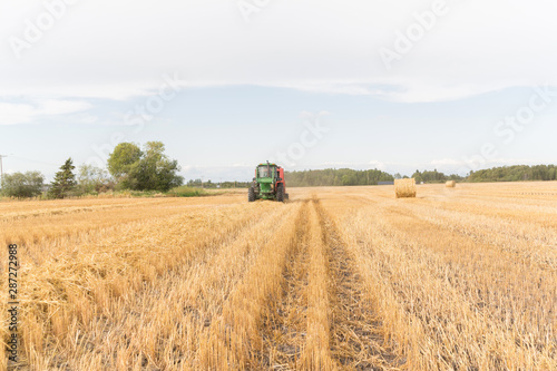 tractor on a swathed field bailing hay