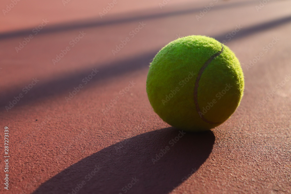 Tennis ball on the tennis court.Tennis balls are covered in a fibrous felt which modifies their aerodynamic properties