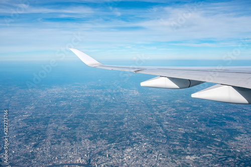 Aerial view of cloud and sky and land with airplane wing from airplane window  Traveling concept.