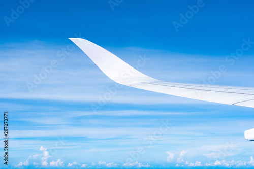 Aerial view of cloud and sky and land with airplane wing from airplane window ,Traveling concept.