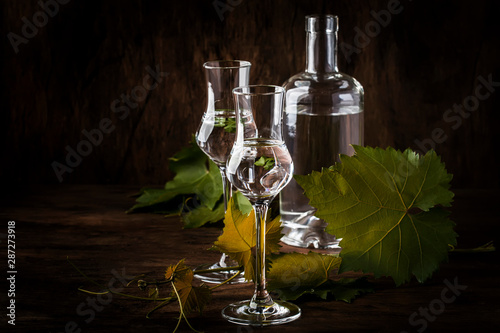 Grape vodka, pisco - traditional Peruvian strong alcoholic drink in elegant glasses on vintage wooden table, copy space photo