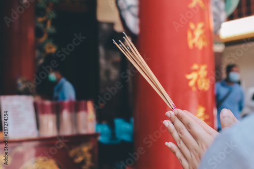 Canvas Print An asian woman keep a lotus, candles and incense sticks in hands for praying res