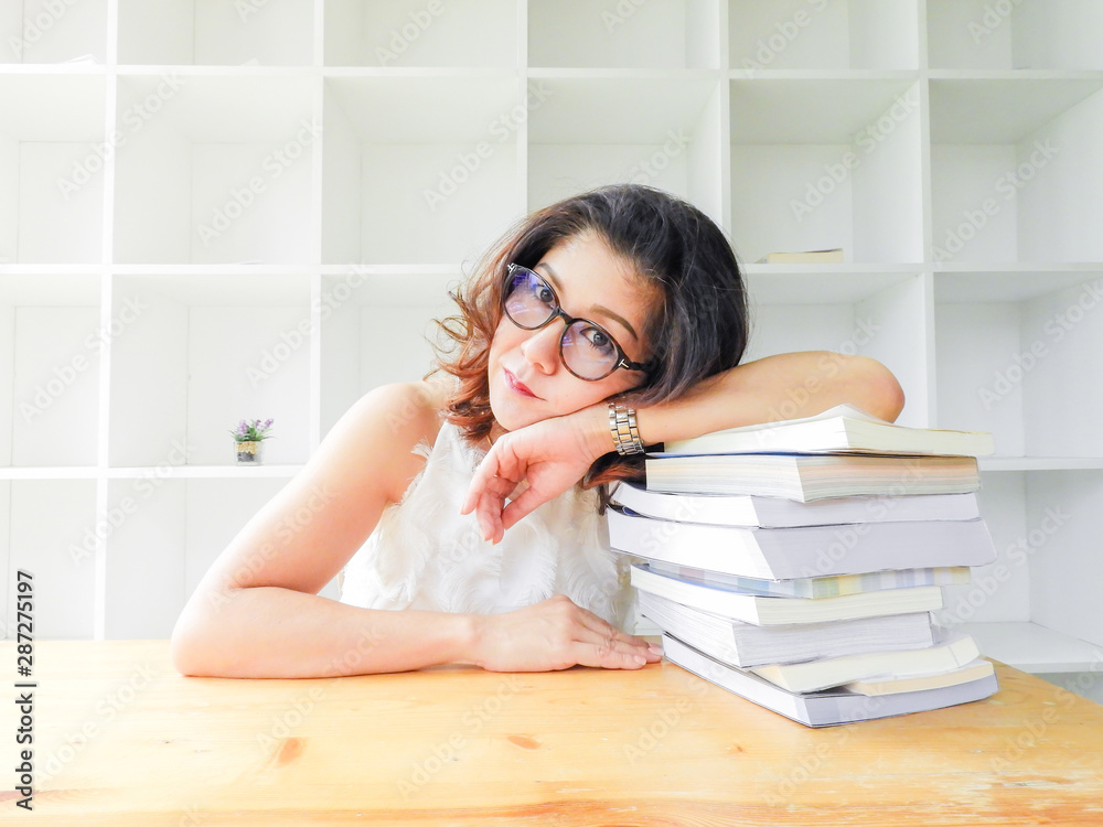 Beautiful women in glasses crushed on the table by a lot of books, very stressed of the study. Beautiful women in glasses crushed on the table by a lot of books, very stressed of the study.