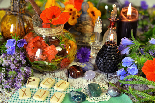 Still life with reiki crystals, runes, black candles and witch herbal potions on table.