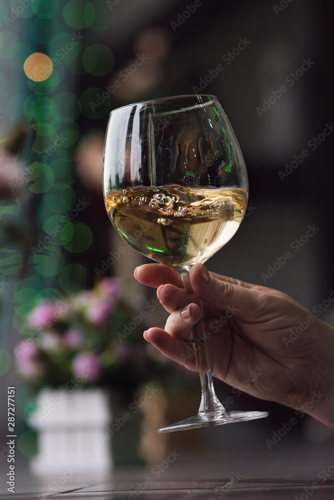 Hand sommelier holding glass of white wine. Swirling wine glass in wine tastings White wine concept. Wine tour. Vertical, cold toning Hand sommelier holding glass of white wine. Swirling wine glass in wine tastings White wine concept. Wine tour. Vertical, cold toning