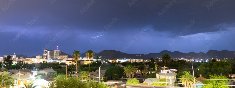 Naklejka premium Purple Blue light illuminates the sky over the buildings homes and hills around Tucson Arizona