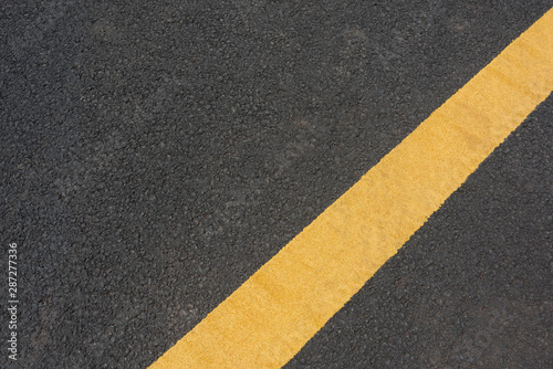 Yellow paint slash mark top view text space on black asphalt road © bqmeng