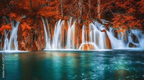 Waterfalls dropping into a natural pool  in a fantasy autumn red forest.