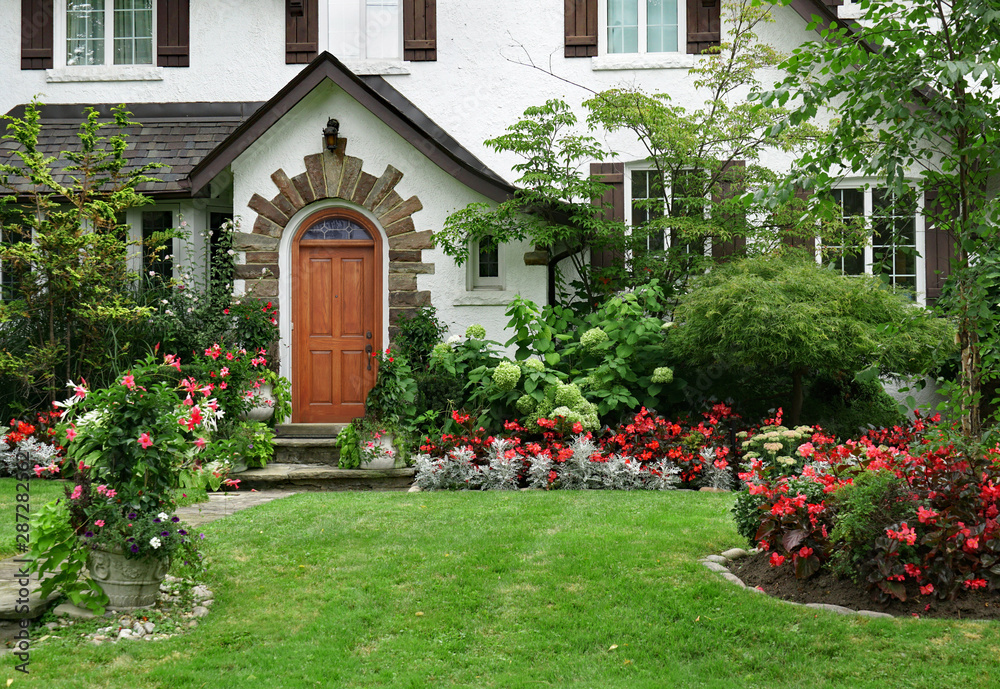 stucco house with wooden front door and flowers in front yard