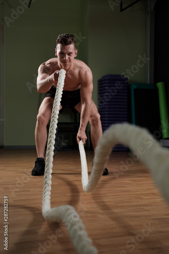 Athlete working out with battle rope at gym