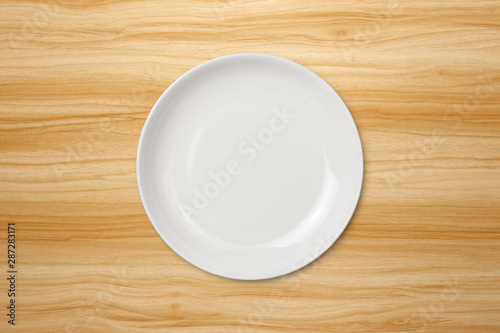 Top view of empty white food plate on a wood background. Template for your design.