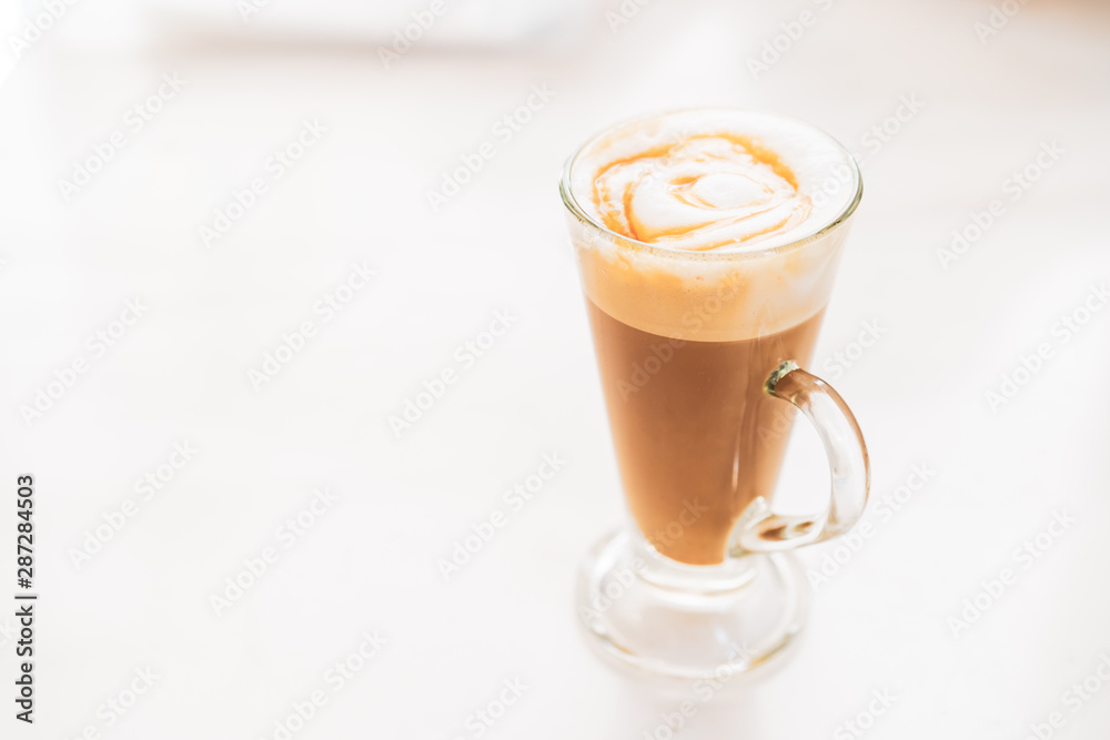 Hot caramel macchiato in a tall glass with caramel sauce on top close up. Hot caramel macchiato in a tall glass with caramel sauce on top close up.