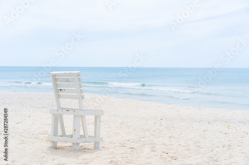 Vintage white wooden chair left on the beach.  The beautiful beach in Thailannd with beautiful blue sky and cloud background. © DG PhotoStock