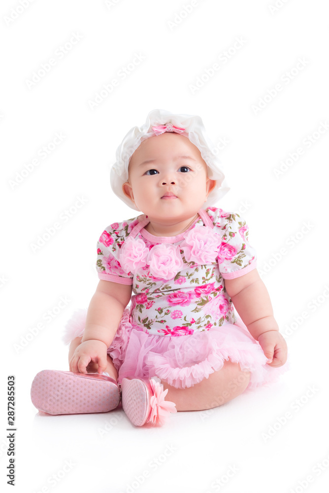 Full length of little asian baby girl in sweet pink dress sitting isolated over white background Full length of little asian baby girl in sweet pink dress sitting isolated over white background