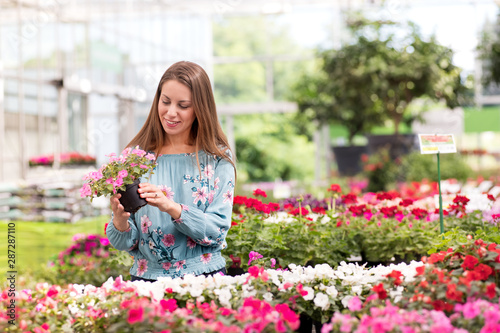 Pretty smiling young woman choosing potted plants