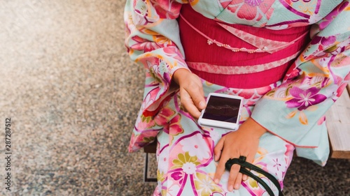 Asian woman wearing beautiful kimono using smartphone and travel in the Japan.Concept of people using mobile technology online.