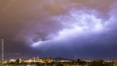 Purple Blue light illuminates the sky over the buildings homes and hills around Tucson Arizona