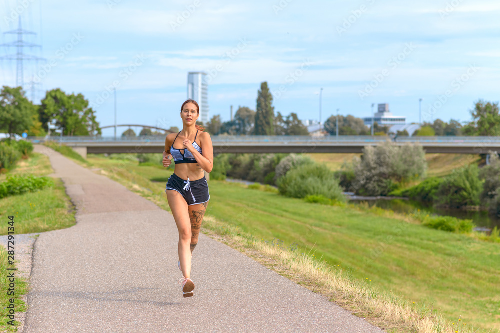 Fit athletic woman running on a country road