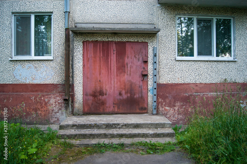 Red door to the utility room for storing equipment of janitors in a five-story city building