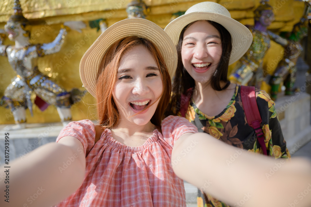 young tourist women in taking selfie picture, enjoy travel in the palace temple in Bangkok of Thailand, Emerald Buddha Temple, Wat Phra Kaew, Bangkok Royal Palace popular tourist place