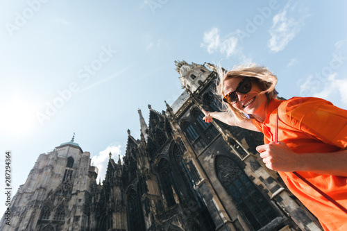 A young woman in a bright orange dress stands on the background of St. Stephen s Cathedral in Vienna  Austria