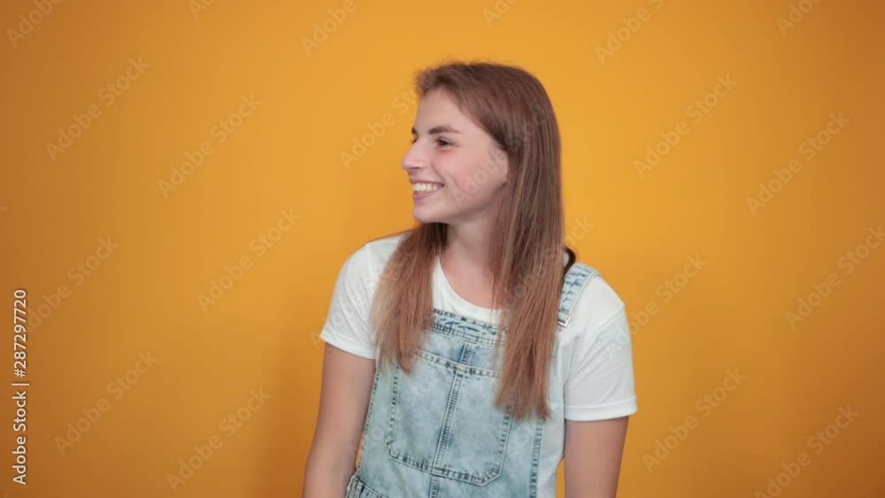 Young woman wearing white t-shirt, over orange background shows emotions