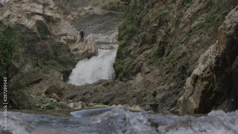 Slow motion shot of man jumping from cliff near water fall. Slow motion shot of man jumping from cliff near water fall.