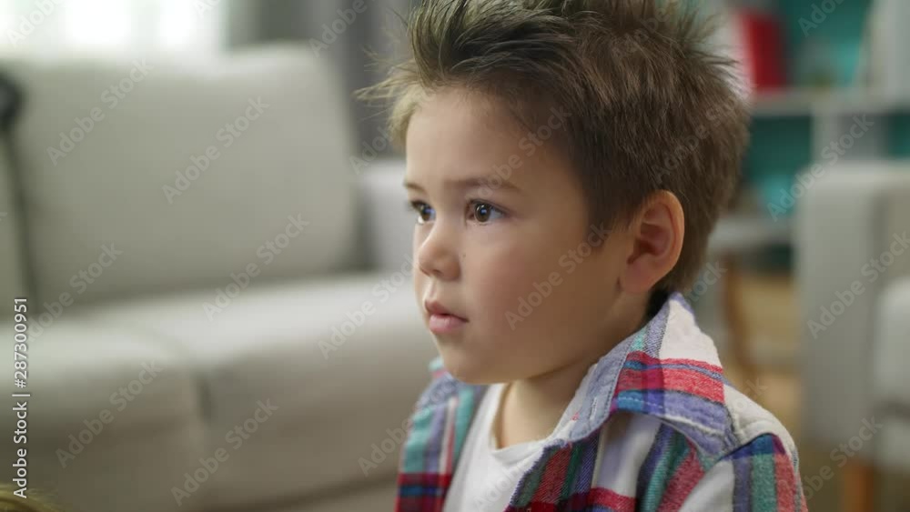 Little boy carefully watches cartoons on TV siting on the floor in living room Little boy carefully watches cartoons on TV siting on the floor in living room