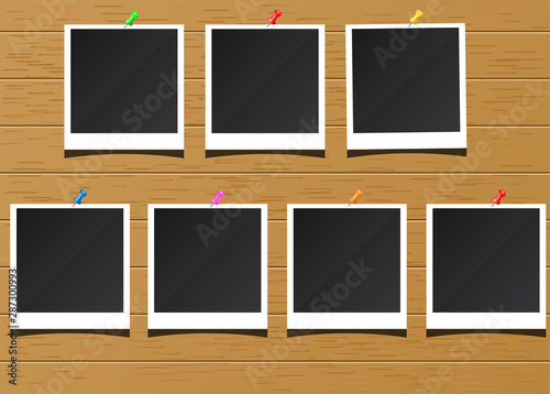 Polaroid photo frames on a wooden board are pinned with pins